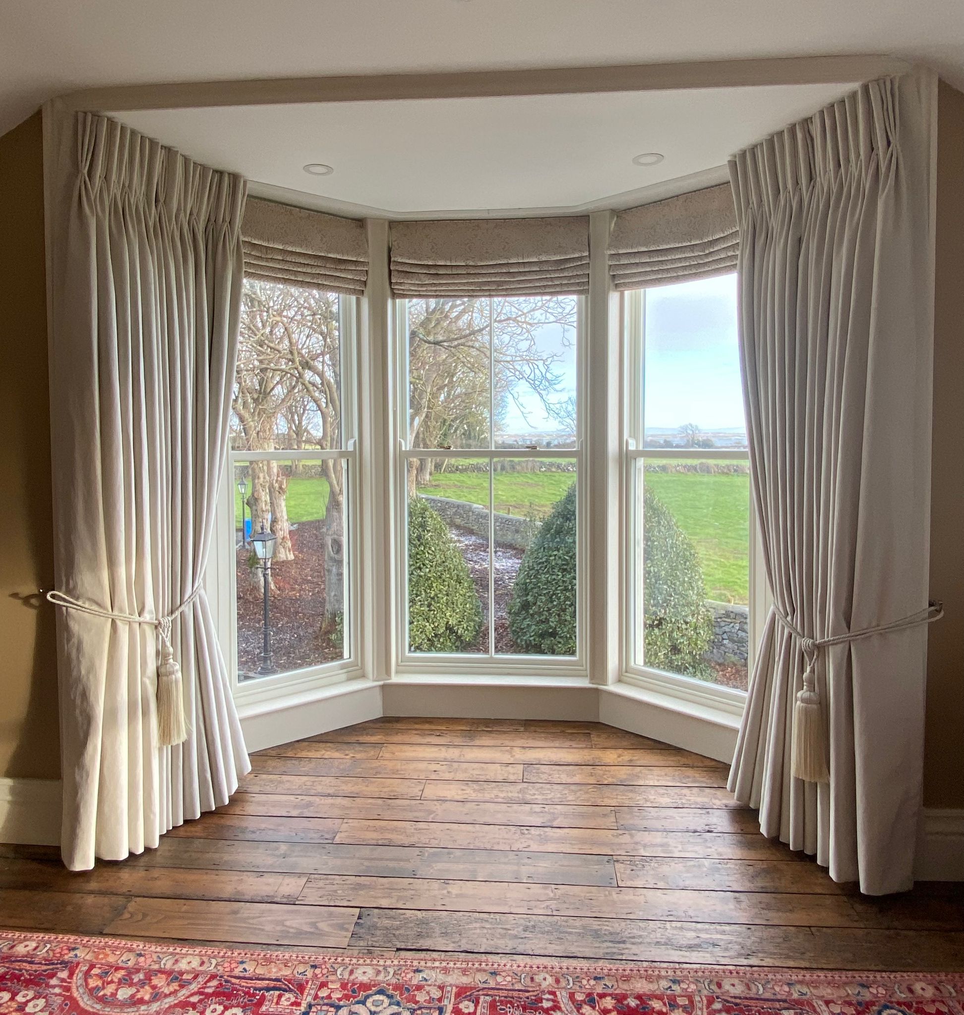 bow bay window with sash windows, roman blinds and curtains that are cream and custom-made