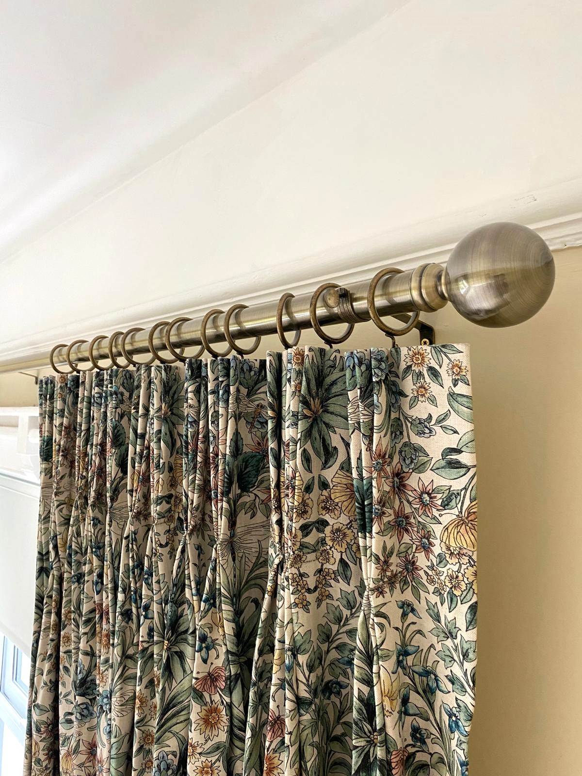 patterned fabric curtain with a french pleat heading on a brushed brass pole